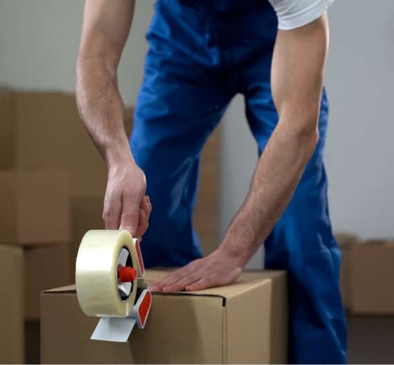 a man at faulkner removals tapes up a box while performing an office relocation