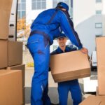 a man at faulkner removals pass a box to another man while doing an office removals job